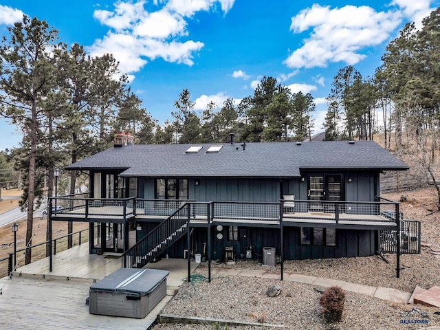 rear view of property featuring central air condition unit, a patio, a wooden deck, and a hot tub