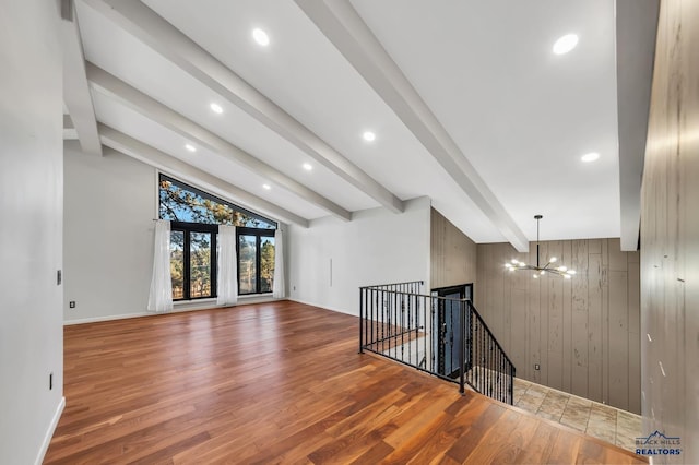 interior space featuring wooden walls, an inviting chandelier, lofted ceiling with beams, and hardwood / wood-style flooring