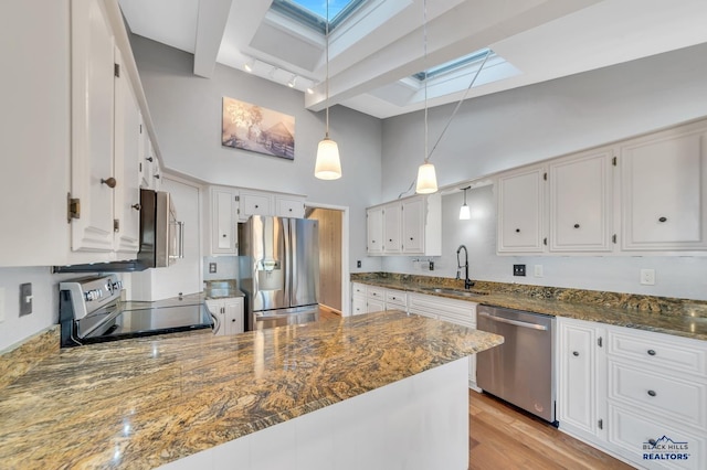 kitchen featuring white cabinetry, a towering ceiling, stainless steel appliances, and a skylight