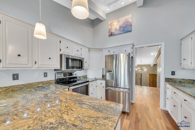 kitchen with appliances with stainless steel finishes, light wood-type flooring, dark stone counters, white cabinets, and a chandelier