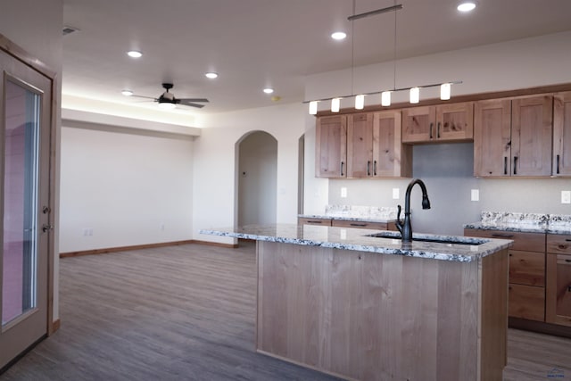 kitchen featuring hardwood / wood-style floors, sink, ceiling fan, light stone countertops, and decorative light fixtures