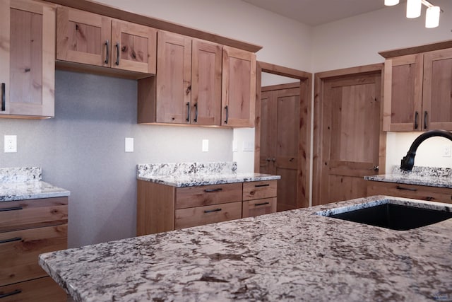 kitchen with light stone counters, sink, and light brown cabinets