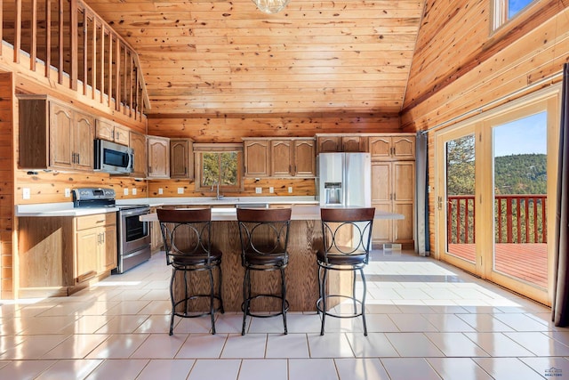 kitchen featuring wooden walls, high vaulted ceiling, stainless steel appliances, and light tile patterned floors