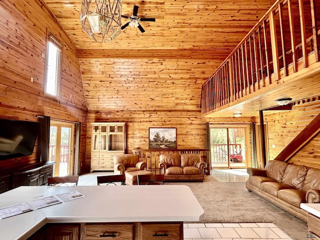 carpeted living room with ceiling fan, high vaulted ceiling, wood ceiling, and wood walls