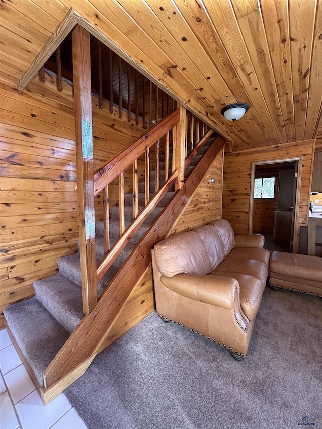 carpeted living room with wooden ceiling and wooden walls