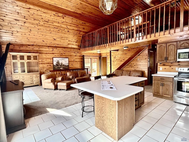 kitchen with wood walls, a center island, appliances with stainless steel finishes, light colored carpet, and wood ceiling