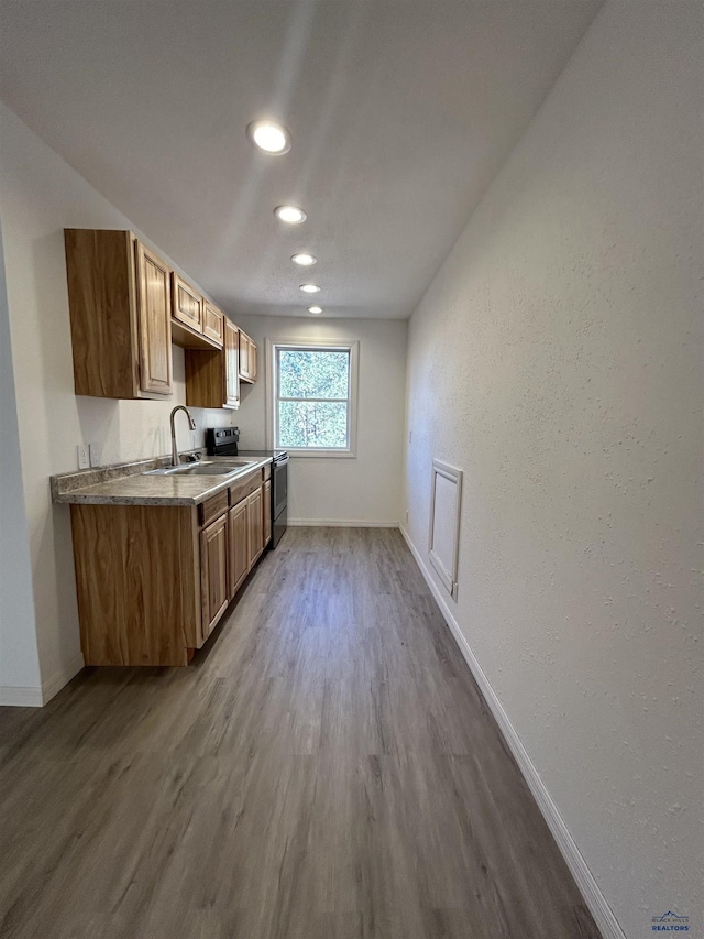 kitchen with wood-type flooring, stainless steel range with electric stovetop, and sink