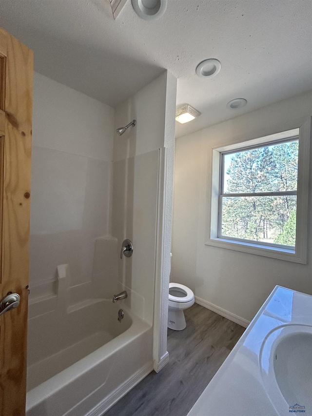 full bathroom featuring hardwood / wood-style flooring, toilet, sink, and bathing tub / shower combination