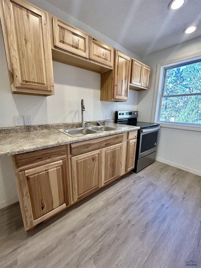 kitchen featuring a textured ceiling, light wood-type flooring, stainless steel range with electric stovetop, and sink