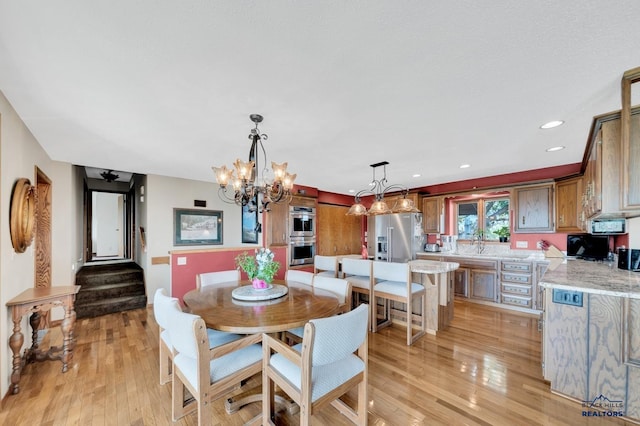 dining area with a chandelier, light wood-type flooring, and sink