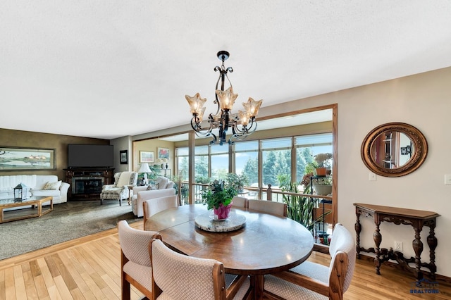 dining room with a textured ceiling, an inviting chandelier, and light hardwood / wood-style flooring