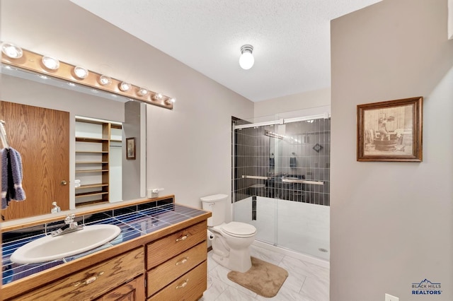 bathroom featuring a textured ceiling, vanity, toilet, and an enclosed shower