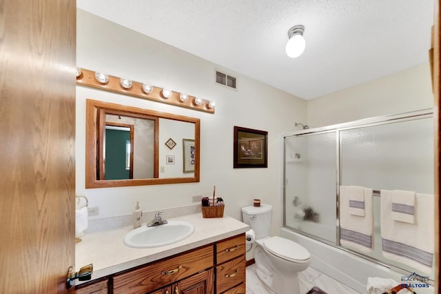 full bathroom featuring combined bath / shower with glass door, vanity, a textured ceiling, and toilet