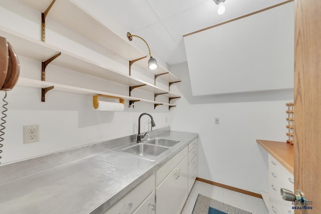 kitchen featuring stainless steel counters, sink, and white cabinets