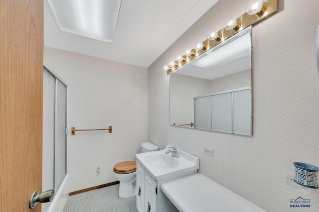 bathroom featuring vanity, toilet, and an enclosed shower