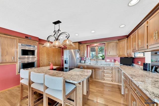 kitchen with a kitchen breakfast bar, light hardwood / wood-style flooring, appliances with stainless steel finishes, decorative light fixtures, and a chandelier