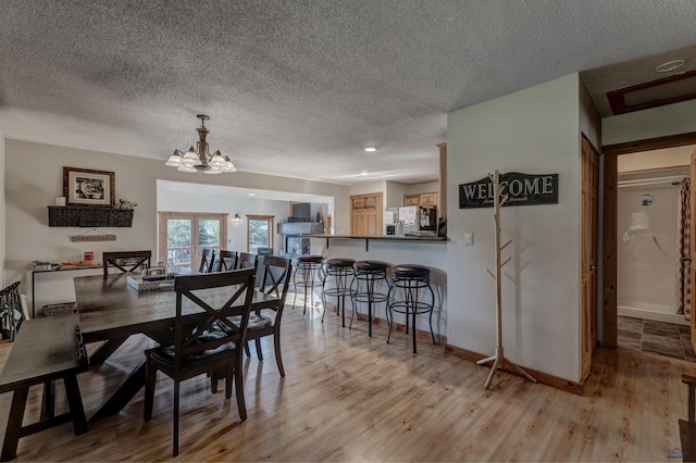 dining room featuring a notable chandelier, light hardwood / wood-style floors, and a textured ceiling