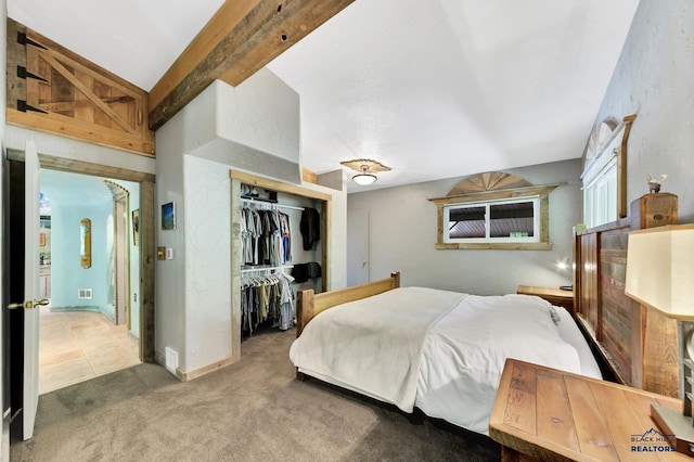 bedroom featuring carpet, beam ceiling, and a closet