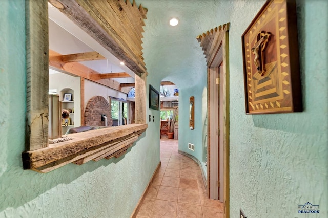 corridor with beam ceiling and light tile patterned floors