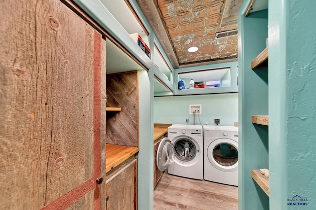 laundry area featuring wood walls, light hardwood / wood-style floors, and washing machine and clothes dryer