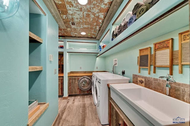 washroom featuring washing machine and clothes dryer, sink, and light wood-type flooring