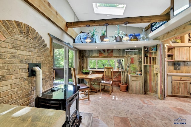 interior space featuring vaulted ceiling with skylight, tile patterned flooring, a wood stove, and brick wall