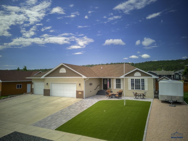 single story home with a patio, a front yard, and a garage