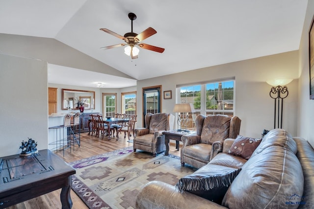 living room with light hardwood / wood-style floors, vaulted ceiling, and ceiling fan