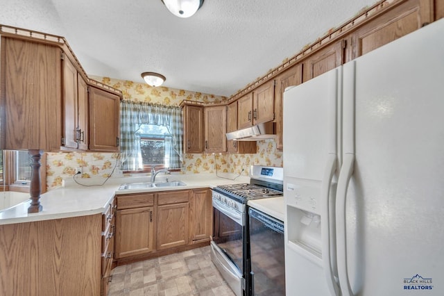 kitchen with gas range, a textured ceiling, white fridge with ice dispenser, and sink