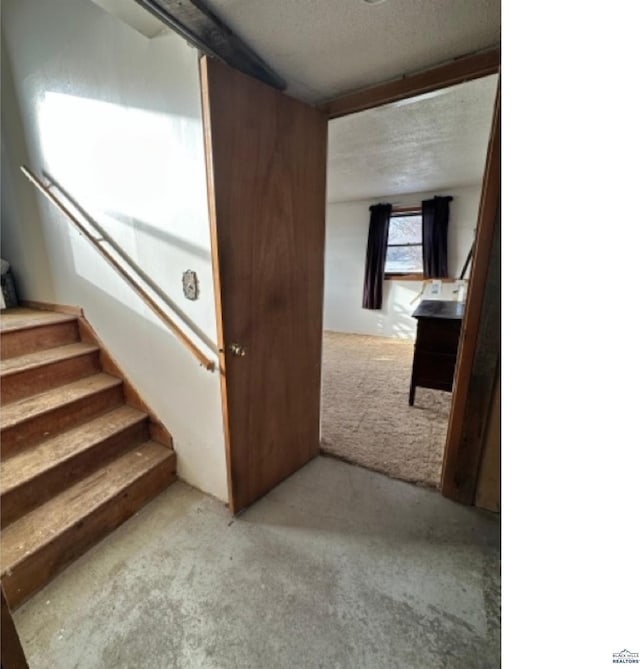 stairway with carpet floors and a textured ceiling