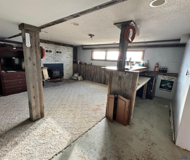 basement with a wood stove and a textured ceiling