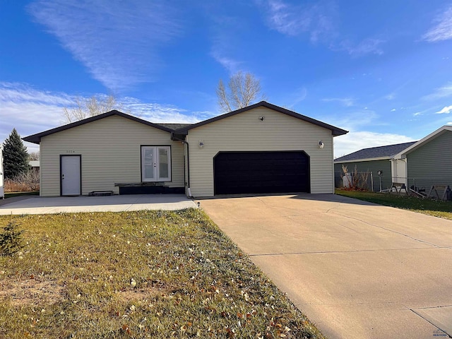 single story home featuring an attached garage, concrete driveway, and french doors