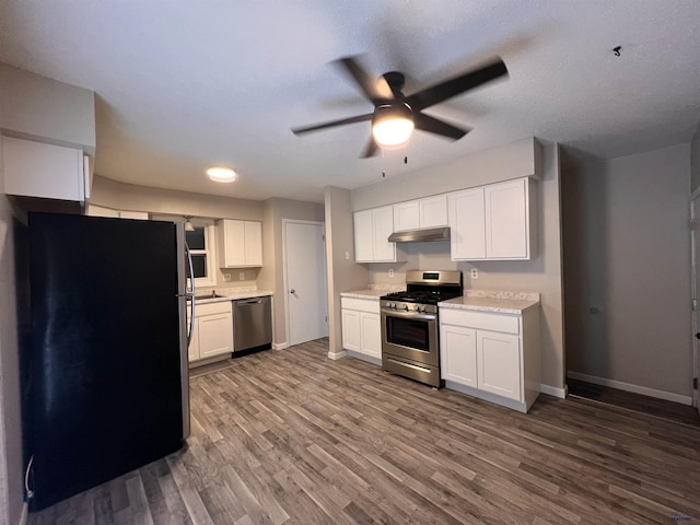 kitchen with stainless steel appliances, wood finished floors, light countertops, and baseboards