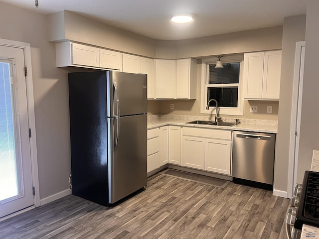 kitchen with dark wood-type flooring, a sink, baseboards, white cabinets, and appliances with stainless steel finishes