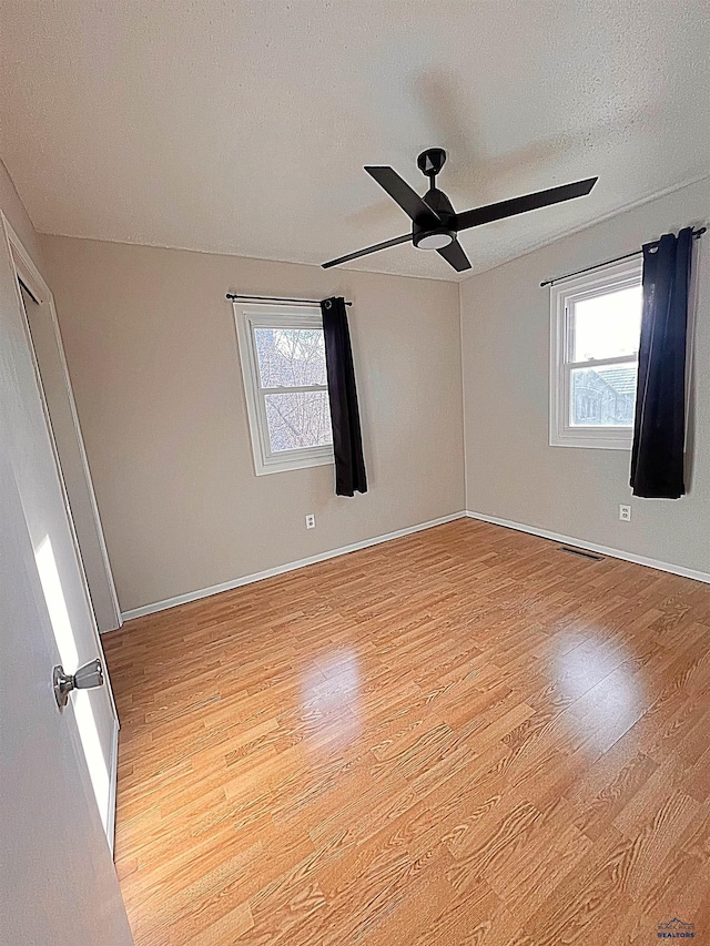 spare room featuring ceiling fan, light hardwood / wood-style floors, and a textured ceiling