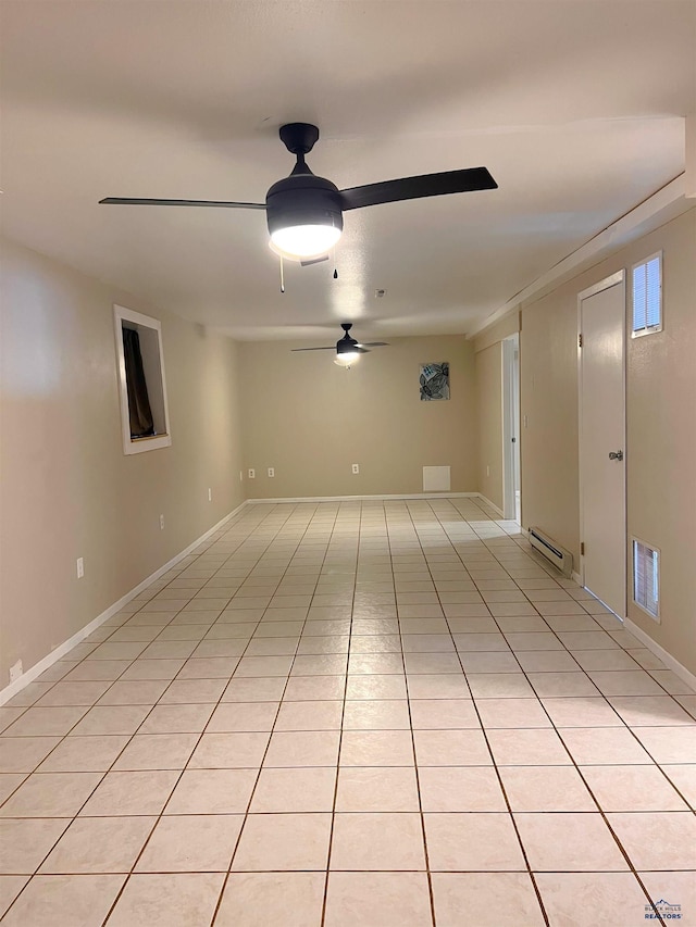 empty room featuring light tile patterned floors, ceiling fan, a baseboard heating unit, visible vents, and baseboards