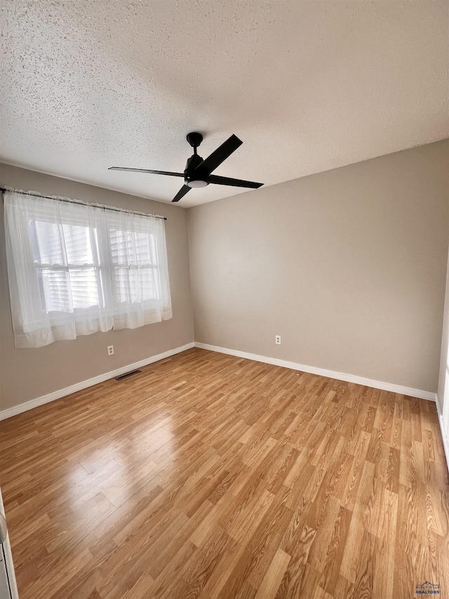 empty room with light wood-type flooring, baseboards, and visible vents