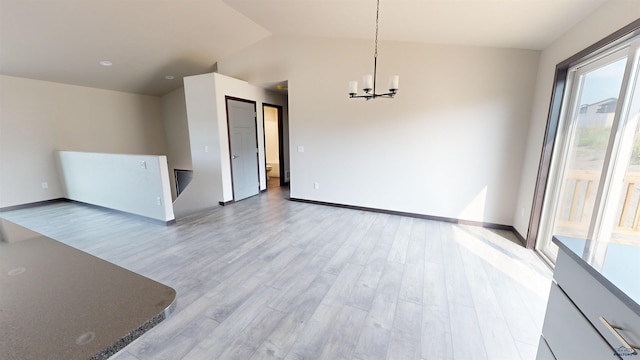 spare room with a notable chandelier, lofted ceiling, and light wood-type flooring