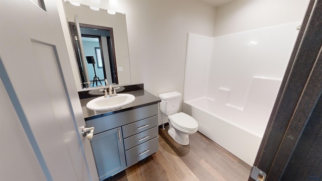 full bathroom with vanity, hardwood / wood-style flooring,  shower combination, and toilet