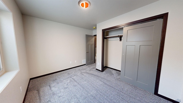 unfurnished bedroom with light carpet and a closet