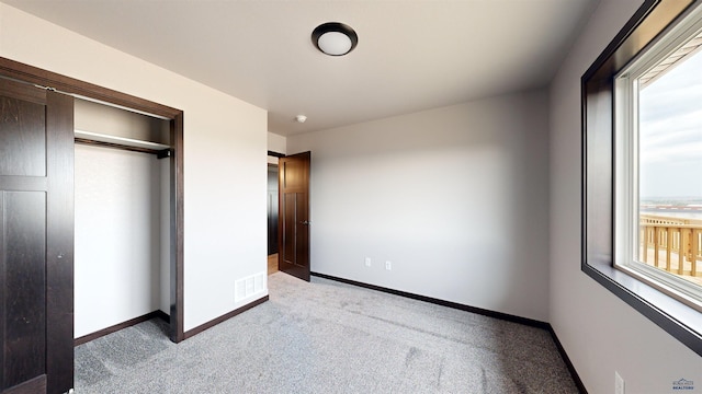 unfurnished bedroom with light carpet and a closet