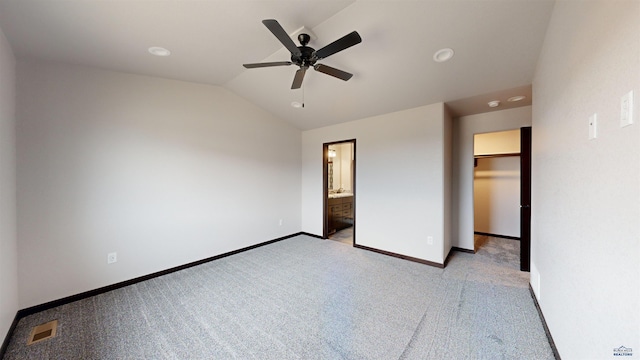 unfurnished bedroom with ensuite bathroom, vaulted ceiling, ceiling fan, a spacious closet, and a closet