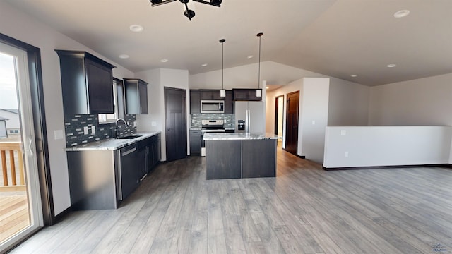 kitchen featuring a center island, sink, vaulted ceiling, decorative light fixtures, and stainless steel appliances