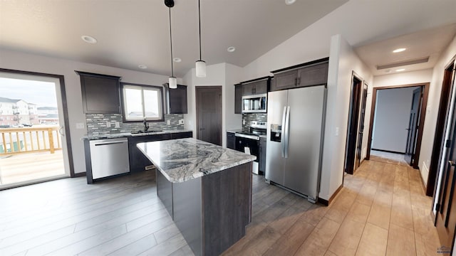 kitchen with sink, a center island, pendant lighting, vaulted ceiling, and appliances with stainless steel finishes