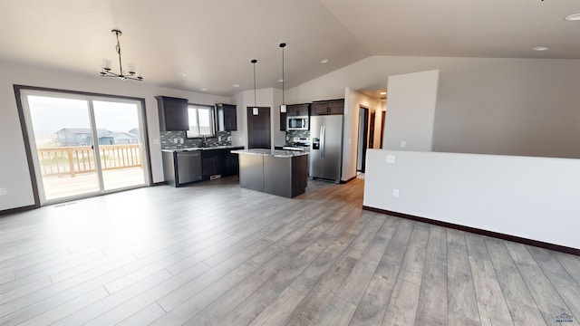 kitchen with stainless steel appliances, backsplash, vaulted ceiling, decorative light fixtures, and a kitchen island