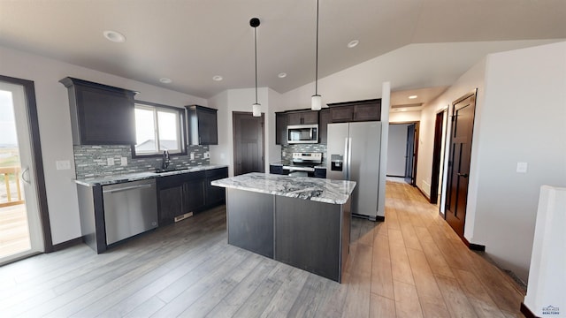 kitchen with sink, tasteful backsplash, vaulted ceiling, a kitchen island, and appliances with stainless steel finishes