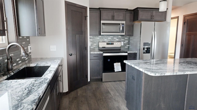 kitchen featuring backsplash, sink, light stone countertops, appliances with stainless steel finishes, and dark brown cabinets