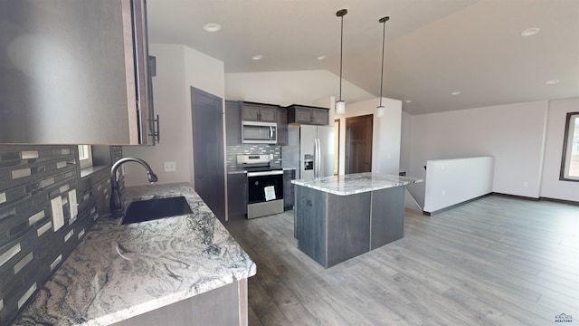 kitchen featuring sink, decorative light fixtures, a kitchen island, light stone counters, and stainless steel appliances