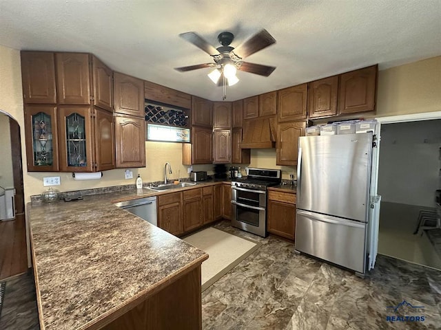 kitchen featuring kitchen peninsula, custom exhaust hood, stainless steel appliances, ceiling fan, and sink