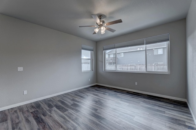 empty room with dark hardwood / wood-style flooring, ceiling fan, and plenty of natural light